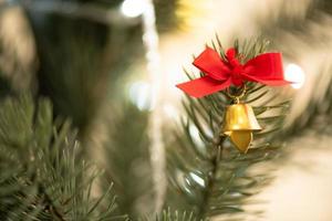 Weihnachtsbaum im Wohnzimmer geschmückt, um sich auf das neue Jahr vorzubereiten. Dekorieren Sie das Wohnzimmer und den Weihnachtsbaum mit einer Schachtel roter Kugeln, goldener Kugeln, goldener Glocken, Schneesterne und Socken. foto