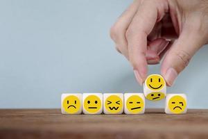 Handwechsel mit Lächeln Emoticon-Ikonengesicht auf Holzwürfel, Hand, die unglückliches Wenden zum glücklichen Symbol umdreht foto