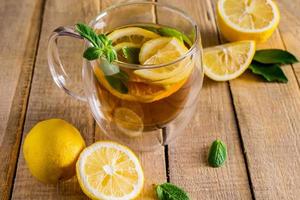 Tee mit Zitrone und Minze in transparenter Tasse foto