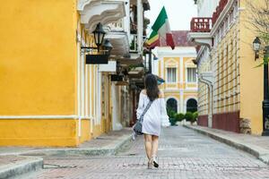 schön Frau auf Weiß Kleid Gehen allein beim das Straßen von das kolonial ummauert Stadt von Cartagena de Indien foto