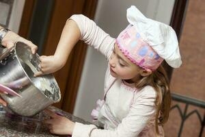 schön blond Mädchen Backen Cupcakes und haben Spaß beim Zuhause foto