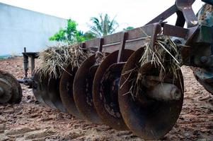 Nahaufnahme von Scheibeneggen auf der Rückseite eines Traktors. schmutzige Stahlschaufeln eines Traktors mit getrocknetem Stroh und Erde foto