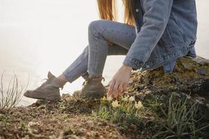 Frau in Jeans auf einer Klippe in der Nähe des Ozeans foto