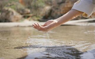 Frau, die Hand in Meerwasser eintaucht foto