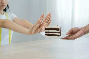 Diät, Diät ungesund asiatisch jung Frau Hand im drücken aus, ablehnen Essen Schokolade Kuchen oder Süss schmecken, Kampf zu behalten es von bekommen Fett wann Person bringen zu Mich. gesund, Ernährung von Gewicht Verlust foto