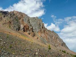 atmosphärisch Landschaft mit felsig Berg Mauer mit spitz oben im sonnig Licht. lose Stein Berg Steigung im das Vordergrund. Scharf steinig Berge. foto