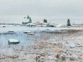 minimalistisch schneebedeckt Winter Landschaft mit authentisch Haus auf das Ufer im das Russisch Dorf Rabocheostrowsk foto