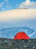 Morgen Aussicht ein Orange verstärkt Zelt gegen das Hintergrund von ein Gletscher auf ein Hohe Höhe Plateau. foto