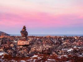 touristisch Pyramide ausgewogen Stapel von Steine beim das Winter Tundra. das Region von das Teriberka. foto