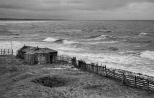 dramatisch schwarz und Weiß Seelandschaft mit ein tobt Weiß Meer und ein Angeln Hütte auf das Ufer. Kandalaksha Bucht. umba. Russland foto