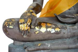 selektiver Fokus auf Nahaufnahmehand der Buddha-Statue, die durch das goldene Blatt beschichtet wird, das auf einem weißen Hintergrund lokalisiert wird foto