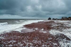 Wellen rollen auf das Ufer von ein alt Angeln Dorf. stürmisch Winter Wellen auf das Weiß Meer. foto