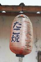 alt und zerrissen traditionell japanisch Geschäft Zeichen Laterne, hing im Vorderseite von das Geschäft foto