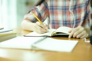 schließen oben jung asiatisch Frau Studie im Vorderseite von das Notizbuch beim Büro. foto