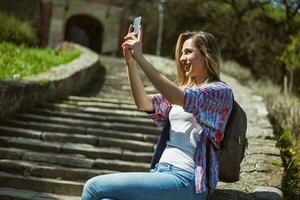 jung Tourist Frau Sitzung durch das Treppe mit ihr Telefon foto