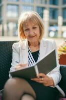 ein Senior Geschäftsfrau Sitzung beim ein Cafe foto