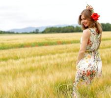 Frau, die in einem Blumenkleid in einem Feld aufwirft foto