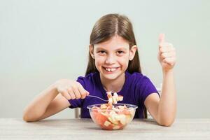 ein Mädchen Essen ein Obst Salat foto