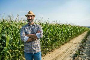 stolz Farmer ist Stehen im seine wachsend Mais Feld foto