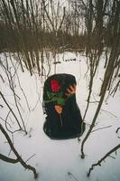 Frau mit ein rot Rose auf das Wald auf Winter Zeit foto