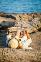 ein Frau lesen beim das Strand foto