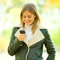 Frau auf Leder Jacke halten das Telefon draußen foto