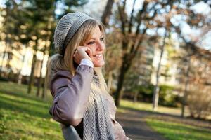 ein Frau im das Park auf das Telefon foto