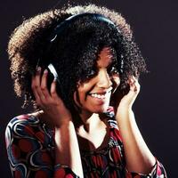 Porträt von ein afrikanisch amerikanisch Frau Hören zu Musik- foto