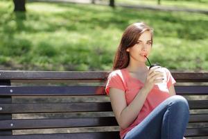 Frau, die Kaffee auf einer Parkbank trinkt foto