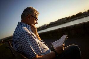 Senior Mann lesen ein Buch draußen foto