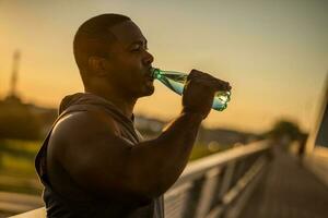 ein afrikanisch amerikanisch Mann Trinken Wasser foto
