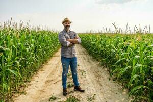 stolz Farmer ist Stehen im seine wachsend Mais Feld foto