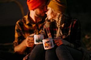 Ein junges Paar, ein Mann und ein Mädchen in bunten Strickmützen, hielten auf einem Campingplatz an foto