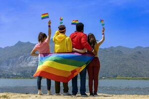 zurück Aussicht von Transgender und Geschlecht Flüssigkeit Gruppe und homosexuell Menschen feiern lgbtq Stolz Monat im bunt Kleid und Regenbogen Flagge zu Umarmung das Unterschied und Verstehen Konzept foto