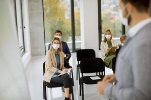 Sprecher und Menge mit Masken in der Besprechung foto