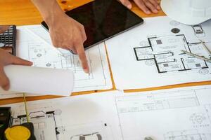 asiatisch Ingenieure Brainstorming und messen zu dokumentieren Kosten Schätzungen und schreiben Fußboden Pläne zum architektonisch und Ingenieurwesen Designs zum Häuser und Gebäude. foto