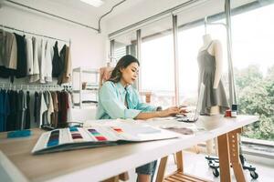 jung Erwachsene asiatisch Frau Designer beschäftigt mit Laptop im Mode wünschen Studio foto