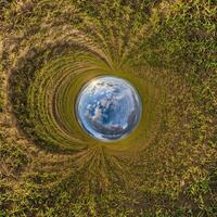 Blau Loch Kugel wenig Planet Innerhalb Grün Gras runden Rahmen Hintergrund. foto