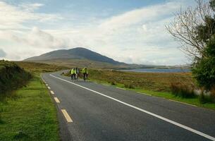 Galway, Irland, 2023, Gruppe von Radfahrer Radfahren Trog connemara durch das Lough inagh mit Berge im das Hintergrund, Bezirk Galway, Irland foto