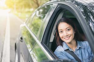 schöne asiatische Frau, die lächelt und ein Auto fährt foto