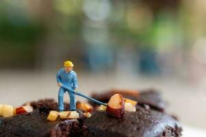 Miniatur Menschen, ein Mitarbeiter ist Herstellung ein Schokolade Brownie foto