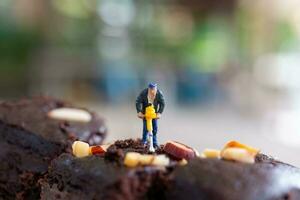 Miniatur Menschen, ein Mitarbeiter ist Herstellung ein Schokolade Brownie foto