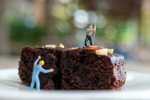 Miniatur Menschen, ein Mitarbeiter ist Herstellung ein Schokolade Brownie foto