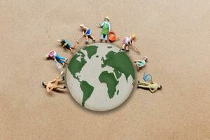 Miniatur Menschen Stehen auf das Globus mit Papier Hintergrund foto