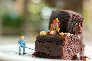 Miniatur Menschen, ein Mitarbeiter ist Herstellung ein Schokolade Brownie foto