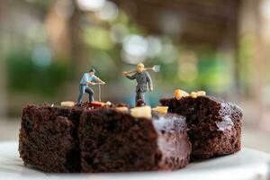 Miniatur Menschen, ein Mitarbeiter ist Herstellung ein Schokolade Brownie foto