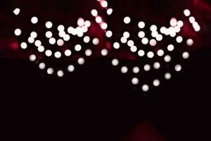 verschwommen Girlande Beleuchtung auf ein dunkel Hintergrund. festlich Weihnachten und Neu Jahr Hintergrund. Sanft Fokus. Bild getönt im Farbe von das Jahr 2023 viva Magenta foto