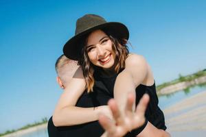 junges Paar ein Mann mit einem Mädchen in schwarzen Kleidern geht auf dem weißen Sand foto