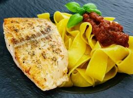 Italienisch Papadelle Pasta mit ein geröstet Lachs Steak und Gemüse foto