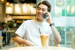 asiatisch Mann Sitzung beim Kaffee Geschäft foto